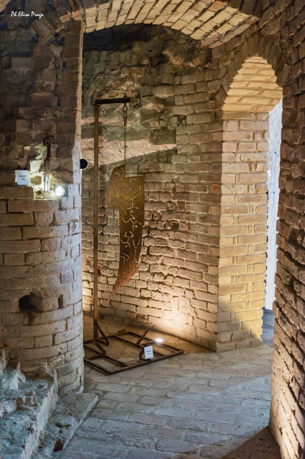 Scultura sospesa in ferro tra gli archi in mattoni