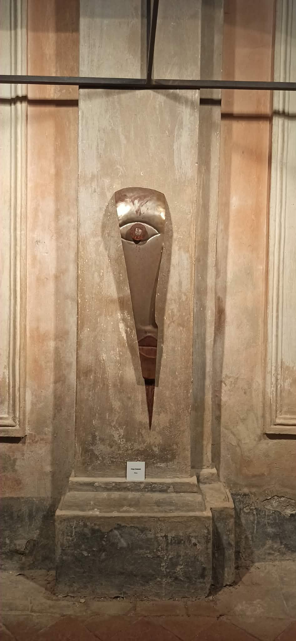 Volto allungato in metallo esposto sulla parete della chiesa